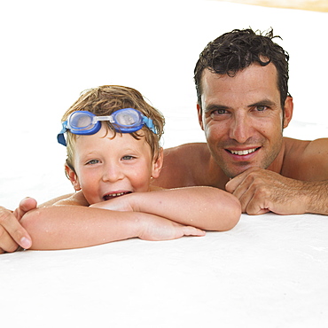 Father and son (6-8) in swimming pool