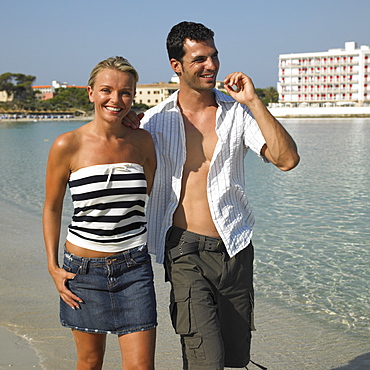 Couple walking on beach, smiling