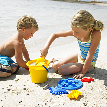 Boy and girl (6-8) on beach making sandcastles