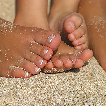 Close up of mother's and daughter's (6-8)feet in sand