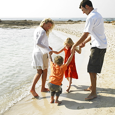 Parents and children (6-8) walking on beach