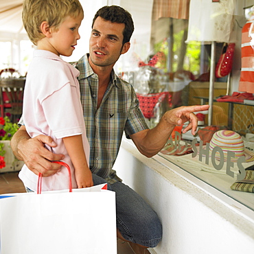 father and son (6-8) window shopping