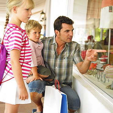 Father and children (6-8) window shopping