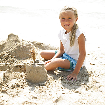 Girl (6-8) making a sandcastle on the beach