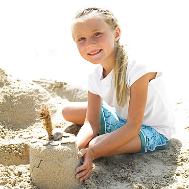 Girl (6-8) making a sandcastle on the beach