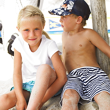 Boy and girl (6-8) on beach by windsurfer