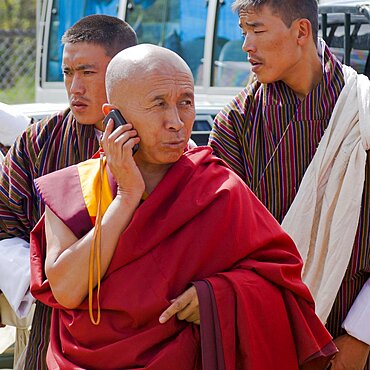 Bhutan, , Red robed Tibetan Buddhist monk talking on his mobile phone.