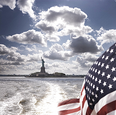 View of Statue of Liberty from rear of boat with Stars and Stripes flag, New York, United States of America, North America