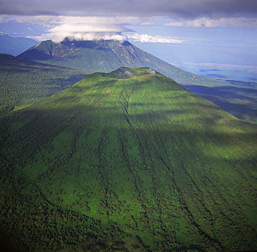 Aerial view of Mount Visoke (Mount Bisoke), an extinct volcano, straddling border of Rwanda and the Democratic Republic of the Congo. with Mount Mikeno in background, Virunga Volcanoes, Great Rift Valley, Africa