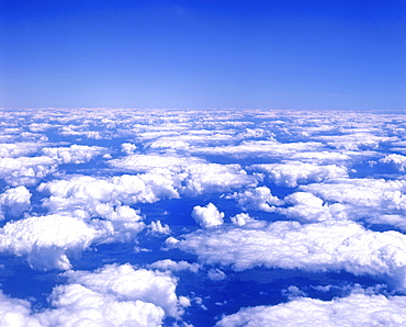 Cumulus clouds in a blue sky viewed from airplane window