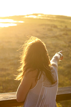 A young woman points out to a water hole at sunset, St. Lucia Wetlands, Kwa-Zulu Natal, South Africa, Africa