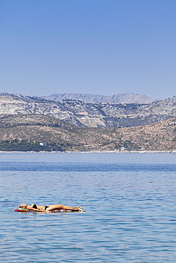 A woman sun bathing on a lilo, Dubrovnik, Dalmatia, Croatia, Europe