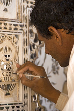 Artisan carrying out repairs on the plasterwork relief at the Amber Fort, Rajasthan, India