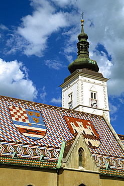 Close-up of tile roof with pattern of shields and clock tower of St. Marks church, Zagreb, Croatia, Europe