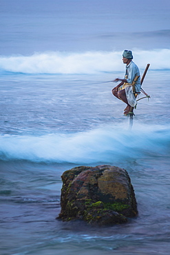 Stilt fishing, a stilt fisherman in the waves at Midigama near Weligama, South Coast, Sri Lanka, Indian Ocean, Asia 