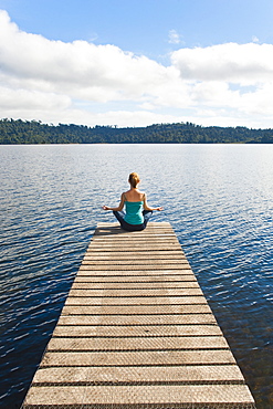 Woman meditating on a jetty, Lake Ianthe, West Coast, South Island, New Zealand, Pacific 