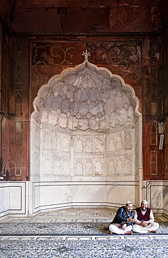 Men sitting by arch at Jama Masjid mosque in Delhi, India, Asia