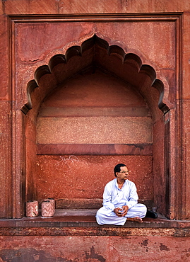 Man sitting in arch at Jama Masjid mosque in Delhi, India, Asia