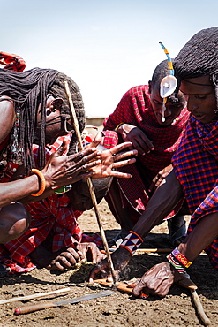 Masai men lighting fire using traditional methods, Masai Mara Village in National Reserve, Kenya, East Africa, Africa