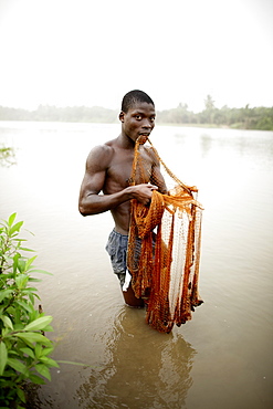 Young man fishing with cast net in river Mono, Agbanakin, near Grand-Popo, Mono Department, Benin