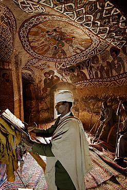 Priest reading in an old goatskin manuscript, Abuna Yemata Guh church with mural painting, Hawzien, Tigray Region, Ethiopia