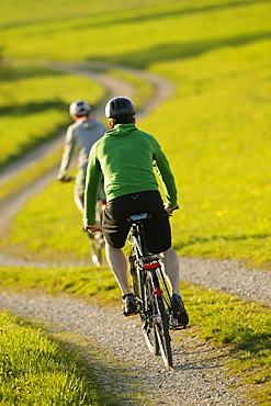 Two cyclists riding e-bikes, Munsing, Upper Bavaria, Germany