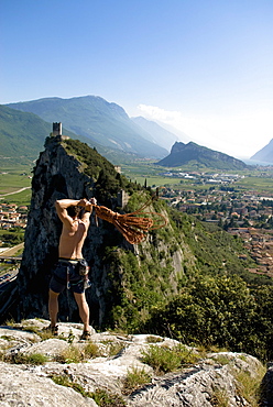 Climber on summit throwing a rope, Arco, Trentino-Alto Adige/Südtirol, Italy