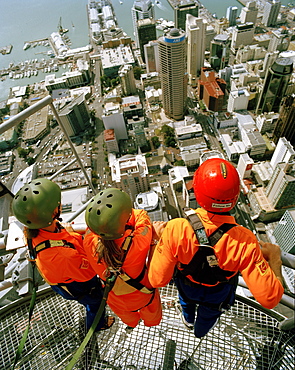 Three people on top of Sky Tower looking over Central Business District and Waitemata Harbour, Auckland, North Island, New Zealand