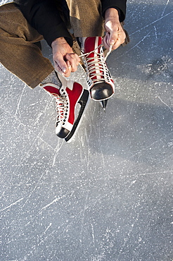 Senior man putting on ice skate, Lake Ammersee, Upper Bavaria, Germany