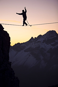 Man balancing on a slackline in sunset, Oberstdorf, Bavaria, Germany