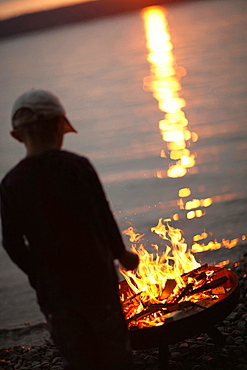 Boy near campfire at lakeside, Lake Starnberg, Bavaria, Germany