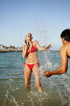 Young couple splashing each other in sea