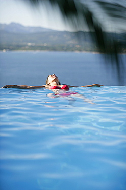 Woman in bikini leaning back in infinity pool, Porto Vecchio, Southern Corse