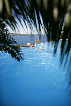 Woman in bikini leaning back in infinity pool, Porto Vecchio, Southern Corse