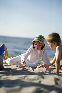 Girl and boy playing at sandy beach of Baltic Sea, Travemuende Bay, Schleswig-Holstein, Germany