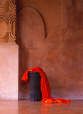 Sarong dressed over a wooden, carved stool set against a polished, decorated wall, Lombok, Indonesia.