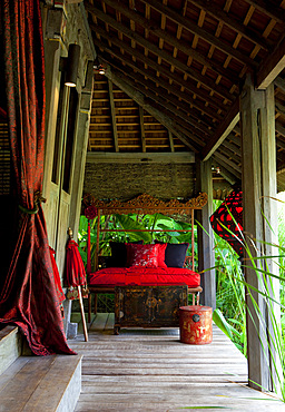 View of terrace of an old Joglo building, decorated with bright, red, Chinese silk. Bali, Indonesia.