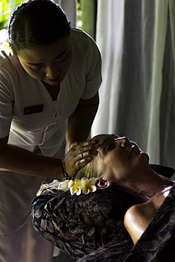 Face massage performed on woman by Balinese therapist. Bali, Indonesia.