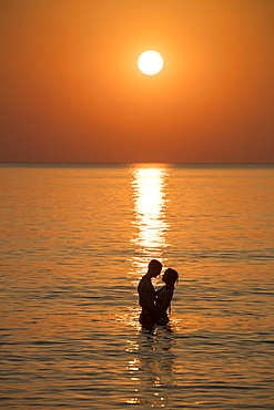 Silhouette of a romantic young couple in the water in front of Ong Lang Beach at sunset, Ong Lang, Phu Quoc Island, Kien Giang, Vietnam, Asia