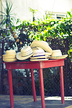 Braided straw hats on a red table in Viñales, Cuba