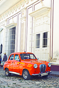 Classic red car in front of a white building in Trinidad, Cuba