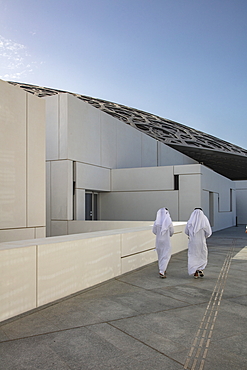 Two Arab men walk running along path outside the Louvre Abu Dhabi Museum, Abu Dhabi, Abu Dhabi, United Arab Emirates, Middle East