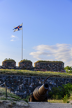 Cannon with flag, recreational area and fortress on the island of Suomenlinna off Helsinki, Finland