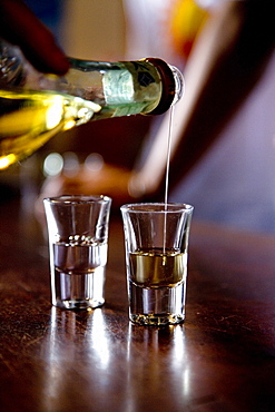 Person pouring Grappa into two glasses, Nardini Grappa Bar, Bassano del Grappa, Veneto, Italy