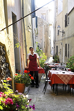 Waitress and tables of a restaurant at an alley, Castelsardo, Sardinia-north, Italy, Europe