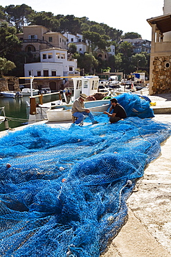 Two fishermen repairing their fishing nets at the harbour of Cala Figuera, Mallorca, Balearic Islands, Mediterranean Sea, Spain, Europe