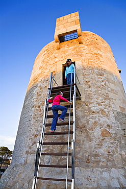 Two girls on the ancient watchtower in the evening light, Cala Santanyi, Mallorca, Balearic Islands, Mediterranean Sea, Spain, Europe