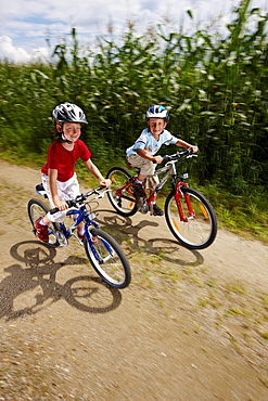 Two children (6-7 years) riding bicycles, Bavaria, Germany