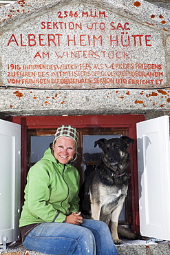 Woman and dog in front of a Albert Heim mountain lodge, Urner Alps, Canton of Uri, Switzerland