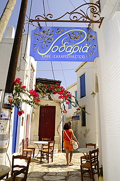 Woman at an alley in the sunlight, Pirgos, island of Tinos, the Cyclades, Greece, Europe